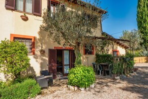 A rustic building with a garden, outdoor seating, and a gravel driveway.