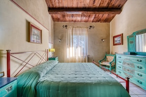 A bedroom with a wooden ceiling, a bed with a green bedspread, a wooden dresser, and a chair. - Apartment 'Il Grappolo E La Rosa Tea' with Shared Garden and Wi-Fi (Montefalco)