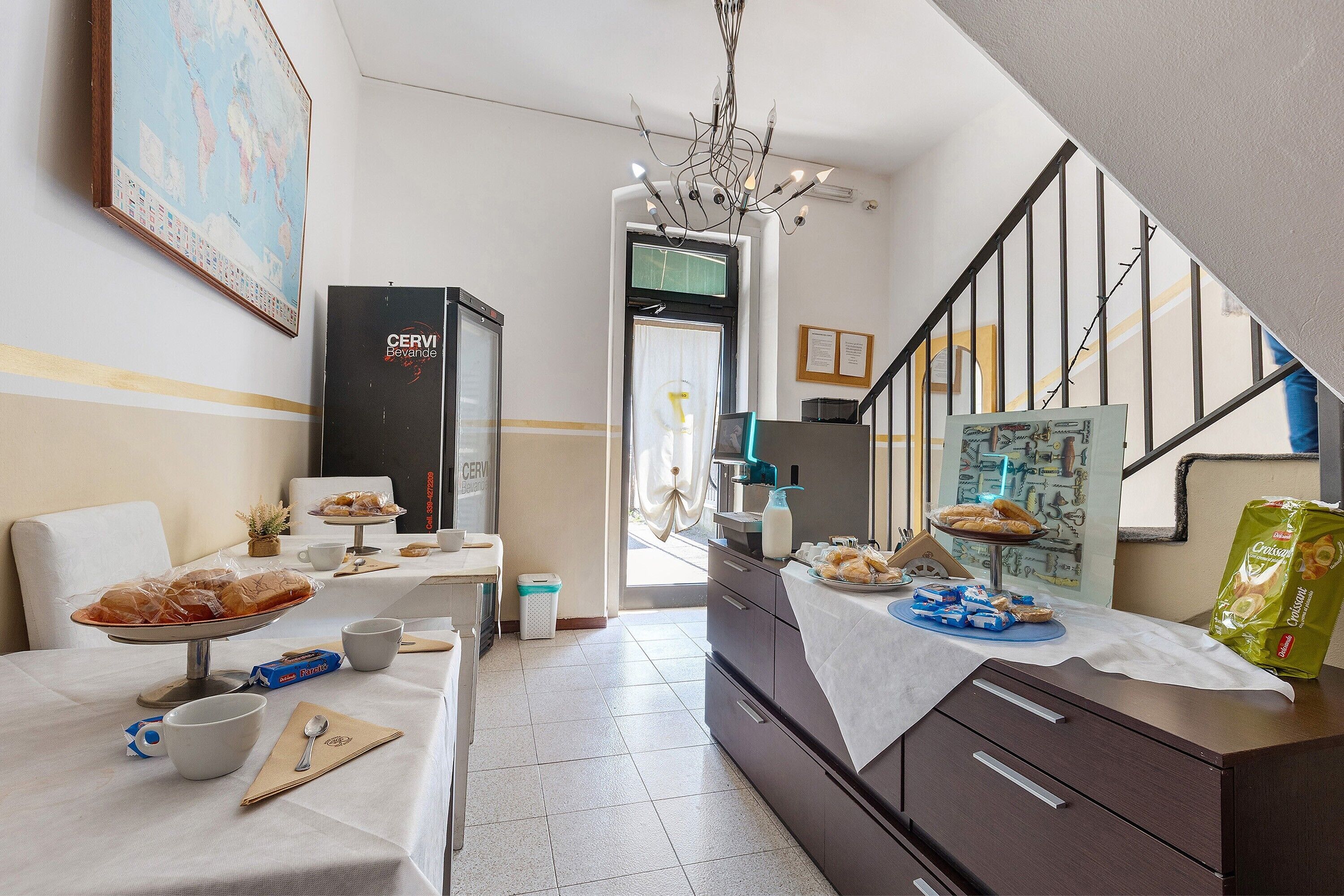 A hotel room with a dining area, a minibar, a staircase, and a world map on the wall.