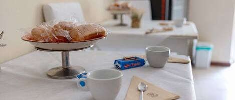 A breakfast setup with a bowl of pastries, a cup, a napkin, a spoon, and a box of Farico.
