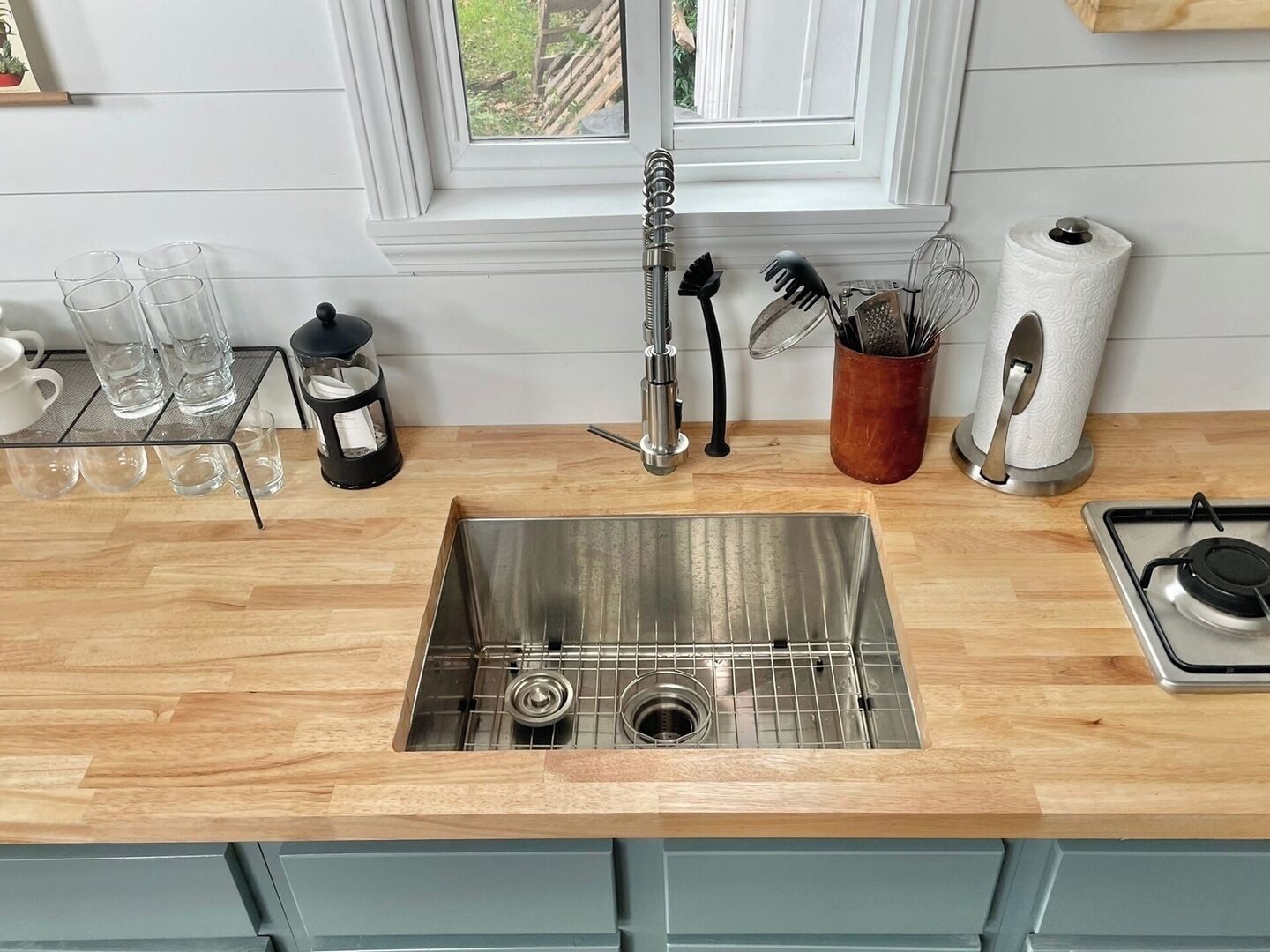 A kitchen with a stainless steel sink, wooden countertop, and light blue cabinets.