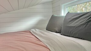 A bedroom with a bed, white walls, and a window. - The Tiny with Big Time Vibes and Walkability (Austin)
