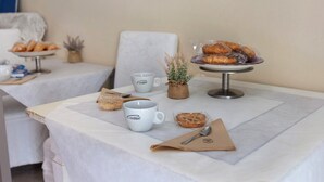A breakfast setup with pastries, a coffee cup, and a spoon on a table.