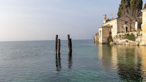 A calm body of water with clear visibility, a historic building with a flag, and a tree on the right.