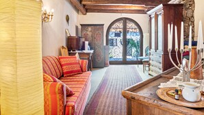 A cozy room with a sofa, a wooden table with a candelabra, and a view through a door.