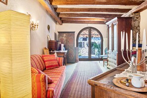 Un'accogliente stanza con un divano, un tavolo di legno con un candelabro e una vista attraverso una porta.