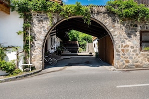 An arched stone entrance to a building with steps leading up to a wooden door.