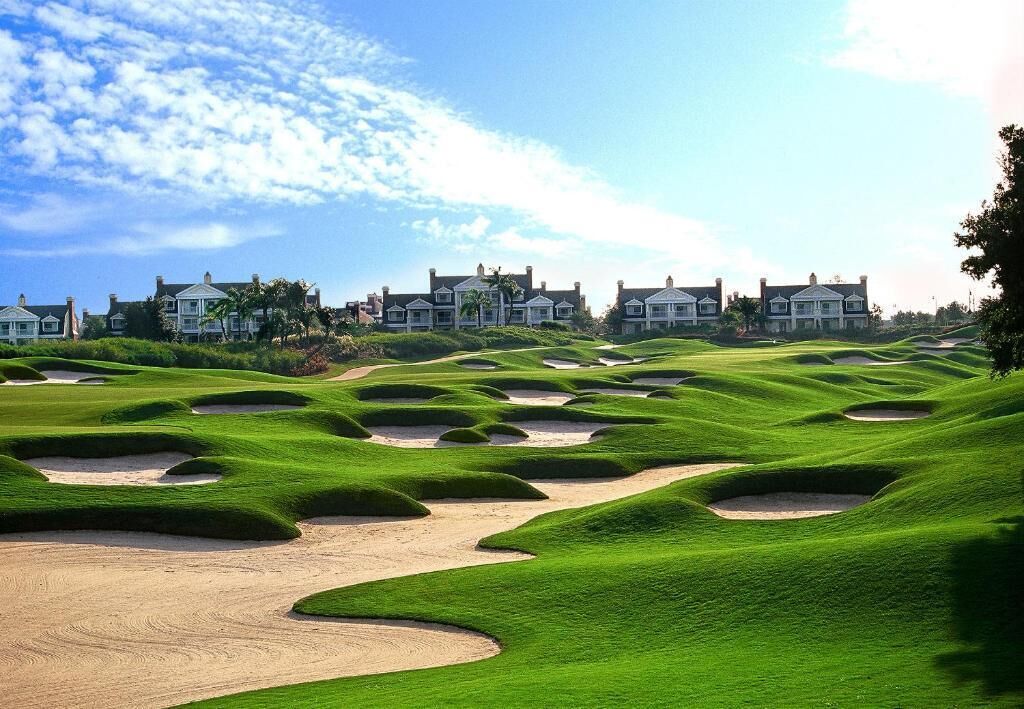 Un parcours de golf avec des bunkers et un club-house en arrière-plan.