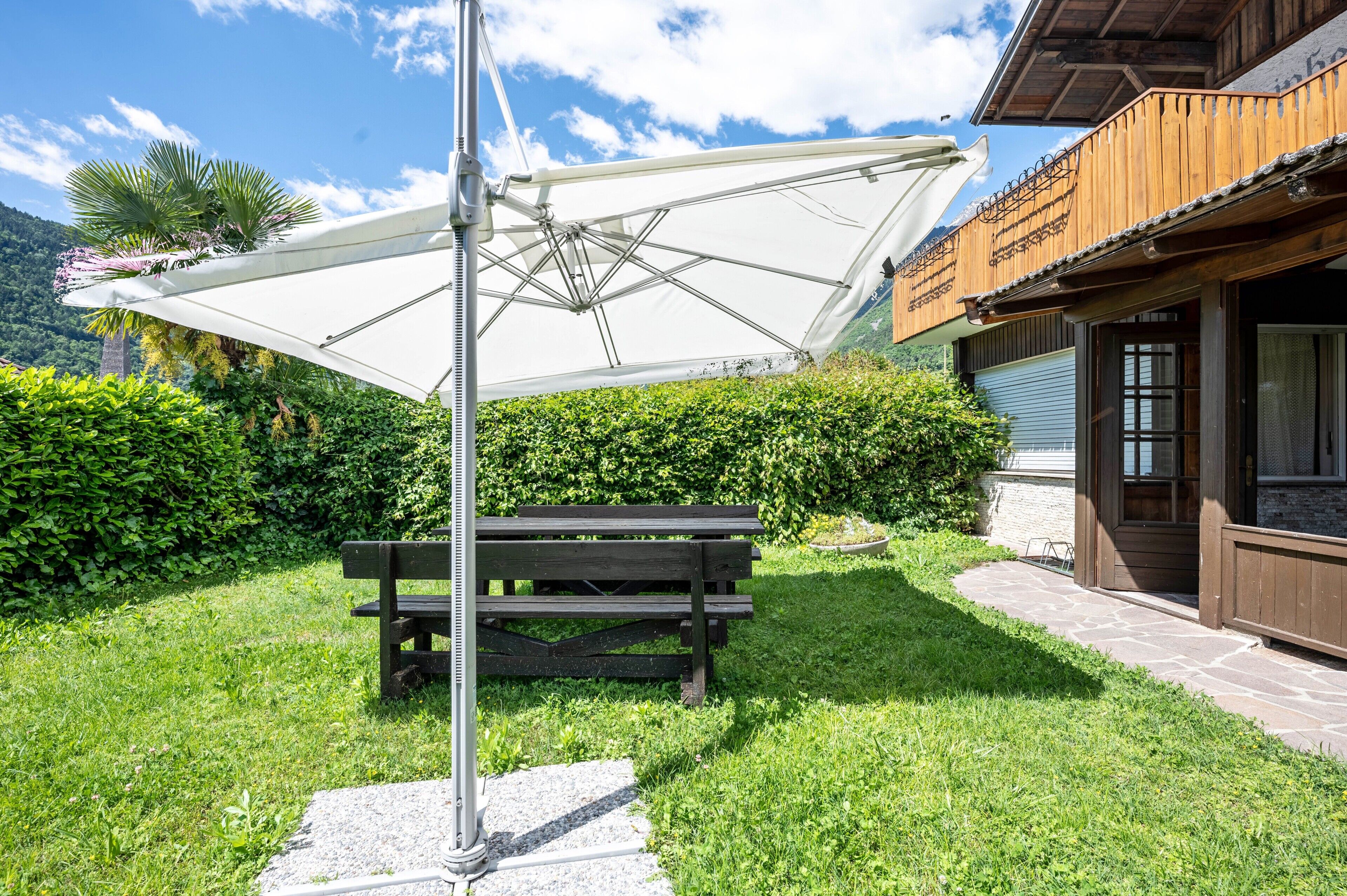 Een houten gebouw met een pad van stenen, een bank en een grote parasol.