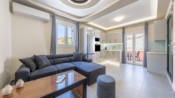 A modern living room with a sectional sofa, a coffee table, and a grey ottoman. - Luxury Stay Apartment with Mountain View, Wi-Fi, and Air Conditioning (Kerkira)