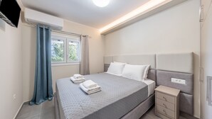 A modern bedroom with a large bed, bedside tables, and a TV mounted on the wall. - Luxury Stay Apartment with Mountain View, Wi-Fi, and Air Conditioning (Kerkira)