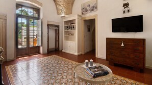 Une pièce spacieuse avec un sol à motifs, un meuble en bois, une télévision et une porte donnant sur un espace extérieur.