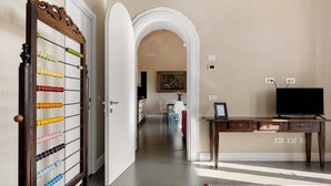 Un pasillo con una puerta abierta que da a un comedor, un escritorio de madera con un televisor y un cuadro colgado en la pared.