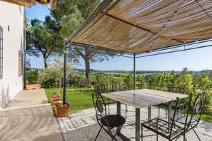 Une terrasse extérieure avec une table et des chaises, une pergola et une vue sur la campagne.