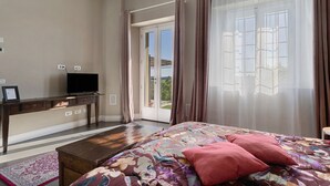 Un dormitorio con cama, un escritorio con televisor, una ventana con cortinas y vistas al exterior.