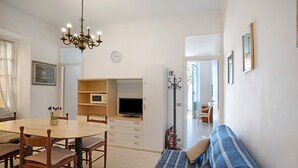 A dining area with a round table and chairs, a television, and a sofa. - Apartment 'Edda' with Sea View and Balcony (Diano Marina)