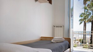 A bedroom with a bed, a radiator, and a balcony with a view of palm trees. - Apartment 'Edda' with Sea View and Balcony (Diano Marina)