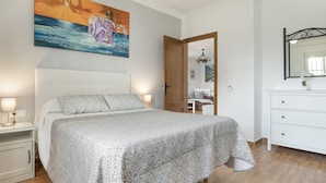 A bedroom with a bed, nightstand, dresser, and a painting on the wall.