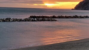 A beach with a rocky breakwater and a sunset. - Apartment for 5 Guests Steps from the Sea (Moneglia)