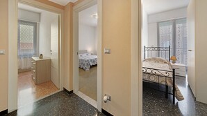 A bedroom with a bed, bedside table, and a small cabinet. - Apartment for 5 Guests Steps from the Sea (Moneglia)