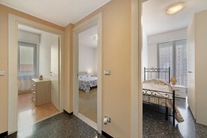 Een slaapkamer met een bed, nachtkastje en een klein kastje.