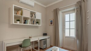 A room with a desk, chair, bed, and a window with curtains.