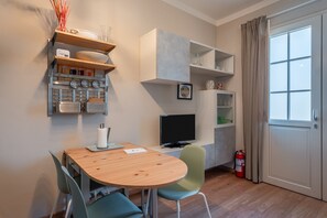 A modern kitchen with wooden cabinets, a dining table, chairs, a television, and a fire extinguisher.