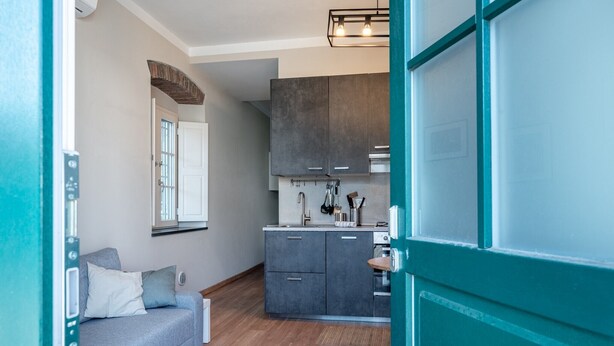 A compact kitchen with grey cabinets, a built-in oven, and a window above the sink.