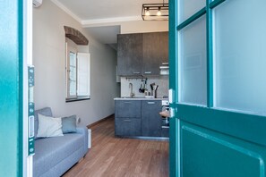 Une cuisine compacte avec des meubles gris, un four encastré et une fenêtre au-dessus de l’évier.