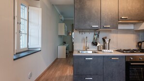 A kitchen with dark cabinets, a gas stove, and a window with blinds.