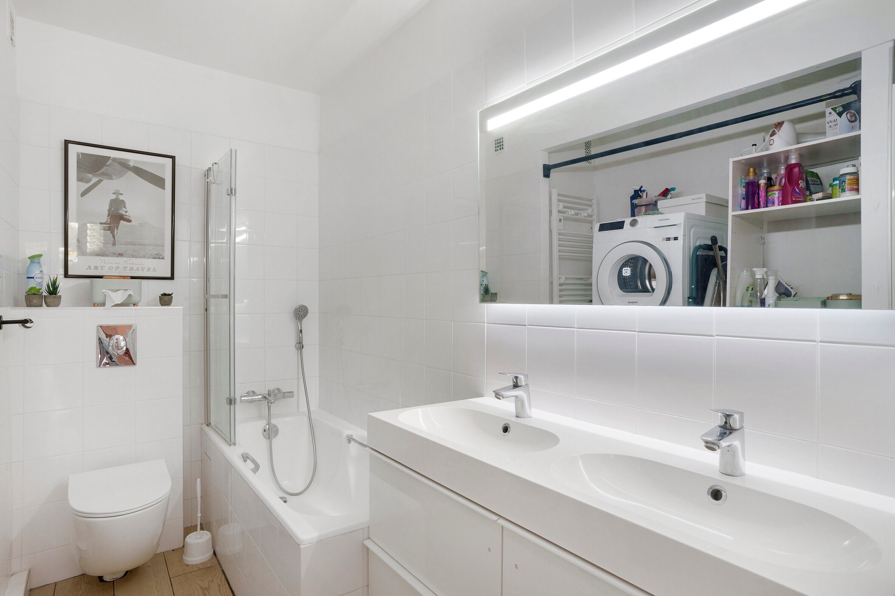 Une salle de bain moderne équipée de toilettes, d’une douche, d’une baignoire, de deux lavabos et d’un grand miroir.