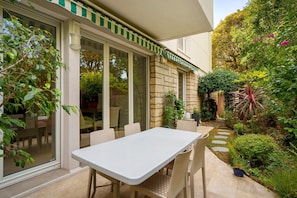 A patio with a table and chairs, a stone wall, and a garden with various plants.