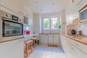 A modern kitchen with white cabinets, a built-in oven, a microwave, and a window with a view.