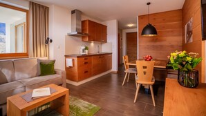 A modern living room with a sofa, coffee table, and a dining area with a wooden table and chairs. - Apartment 'Lavender' with Mountain View, Shared Pool and Wi-Fi (Schenna)