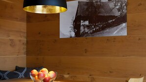A wooden interior with a table, a bowl of fruit, a black and gold pendant light, and a black and white photograph on the wall. - Apartment 'Lavender' with Mountain View, Shared Pool and Wi-Fi (Schenna)