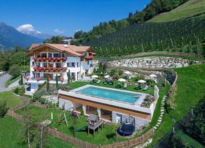 Un edificio de dos plantas con piscina, mobiliario exterior y vistas del paisaje circundante.