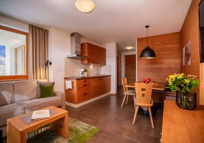 Un salon moderne comprenant un canapé, une table basse et un coin repas avec une table et des chaises en bois.