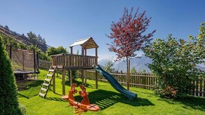 A playground with a slide, swings, and a climbing structure. - Apartment 'Sonnenblume' with Mountain View, Shared Pool and Wi-Fi (Schenna)