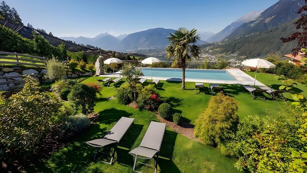 A pool area with lounge chairs and umbrellas, surrounded by well-maintained greenery and mountains in the background. - Apartment 'Sonnenblume' with Mountain View, Shared Pool and Wi-Fi (Schenna)