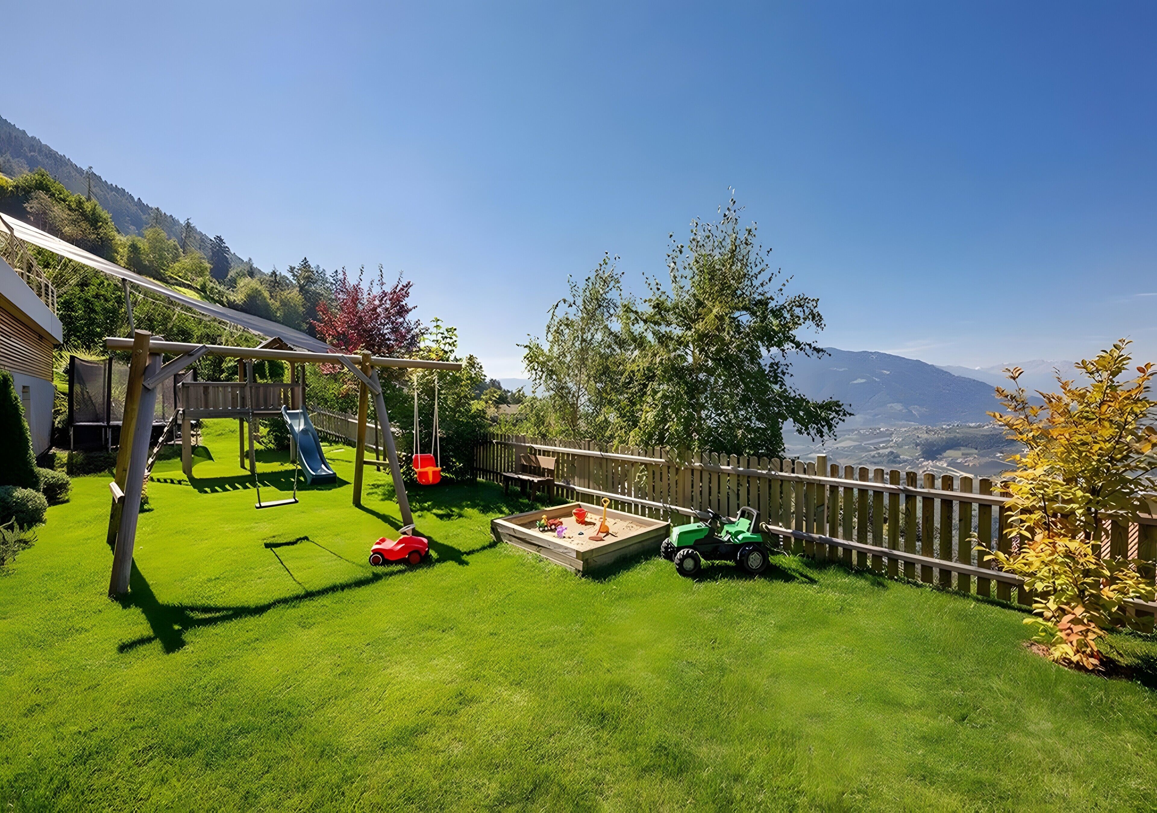 A backyard with a swing set, a slide, a sandbox, and a green toy car.