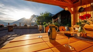 A wooden table with a vase and wine glasses, a wooden bench, and a view of mountains and the sea. - Apartment 'Sonnenblume' with Mountain View, Shared Pool and Wi-Fi (Schenna)