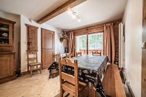 A rustic kitchen with wooden cabinets, a dining table with a black tablecloth, and a mounted deer head.
