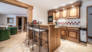 A kitchen with wooden cabinets, a bar stool, and a tiled backsplash.