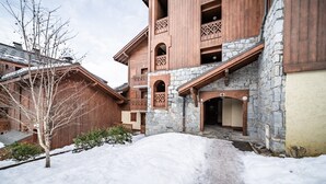 A multi-story building with stone and wooden architecture, a snow-covered ground, and a visible entrance.