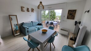 Ein modernes Wohnzimmer mit Sofa, Esstisch, Stühlen, einem großen Spiegel und Blick ins Freie.