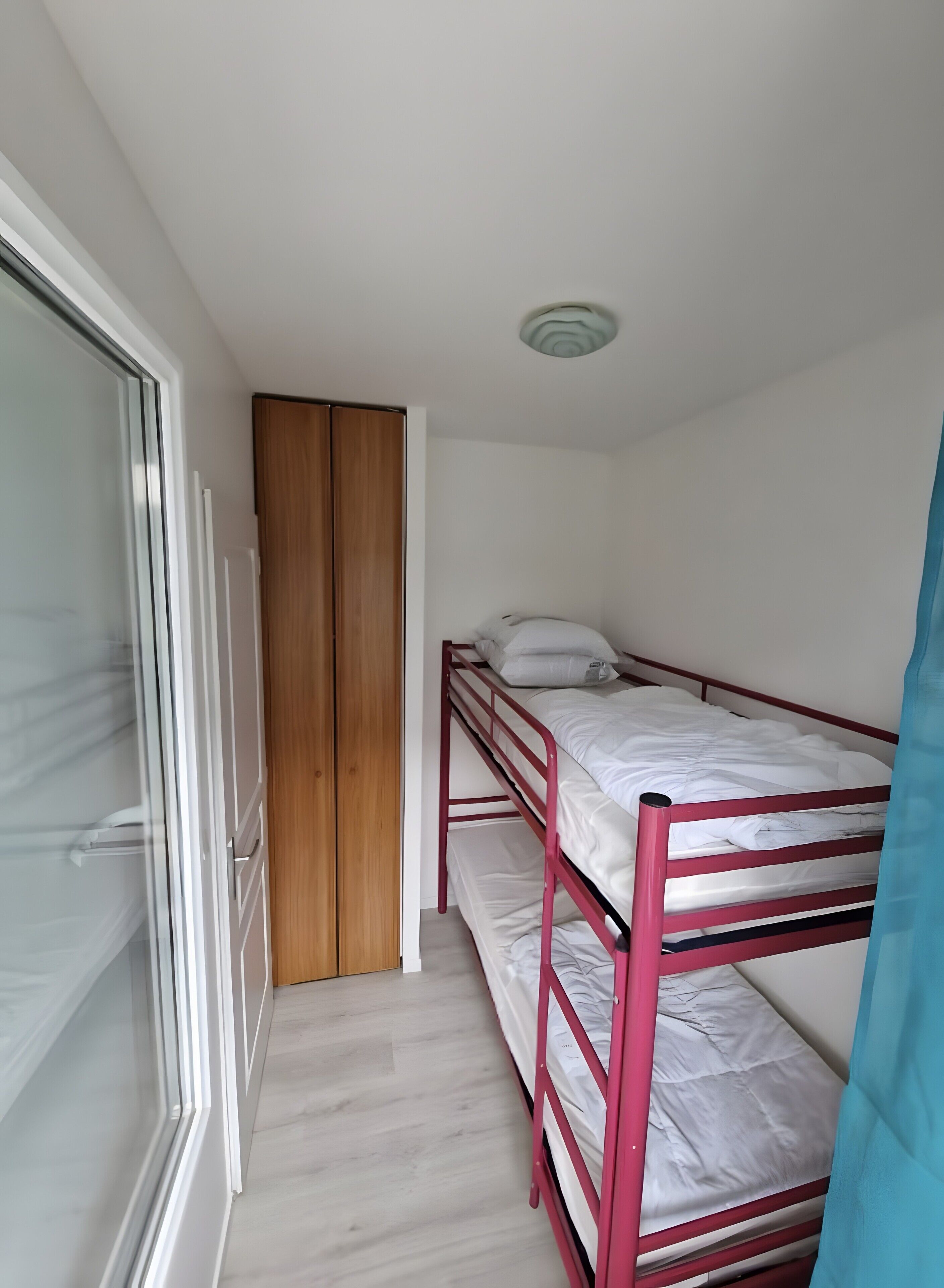 Una habitación pequeña con cama individual, un armario de madera y una puerta corredera.