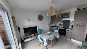 Eine moderne Küche mit Essbereich, einem Fernseher und einer Uhr an der Wand.
