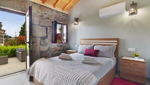 Ein Schlafzimmer mit Steinwand, einem Bett mit weißer Bettwäsche, einem Nachttisch und einem roten Teppich.