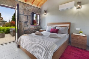 A bedroom with a stone wall, a bed with white bedding, a nightstand, and a red rug.