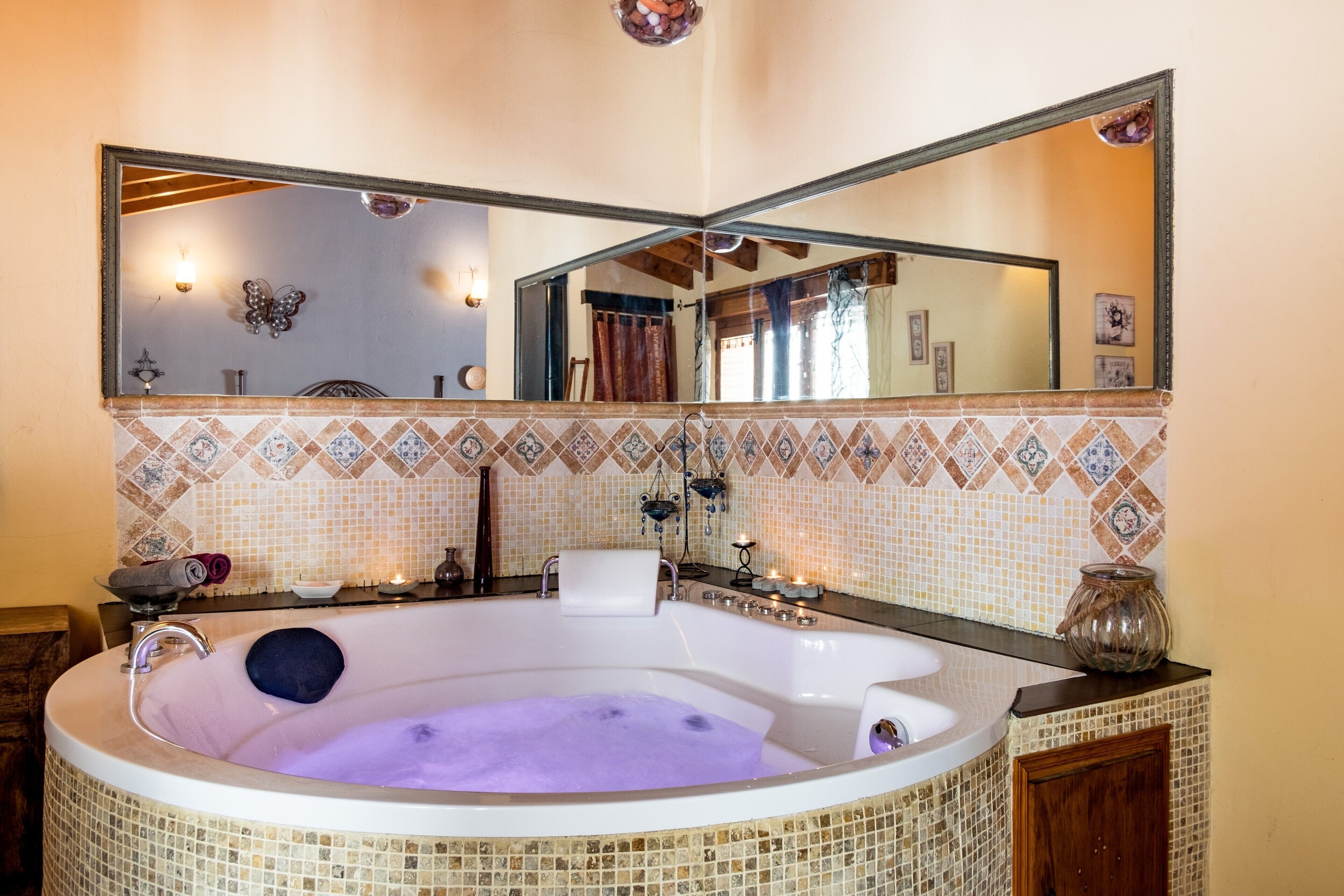 Une salle de bain avec une grande baignoire, un miroir et un mur recouvert de carreaux.